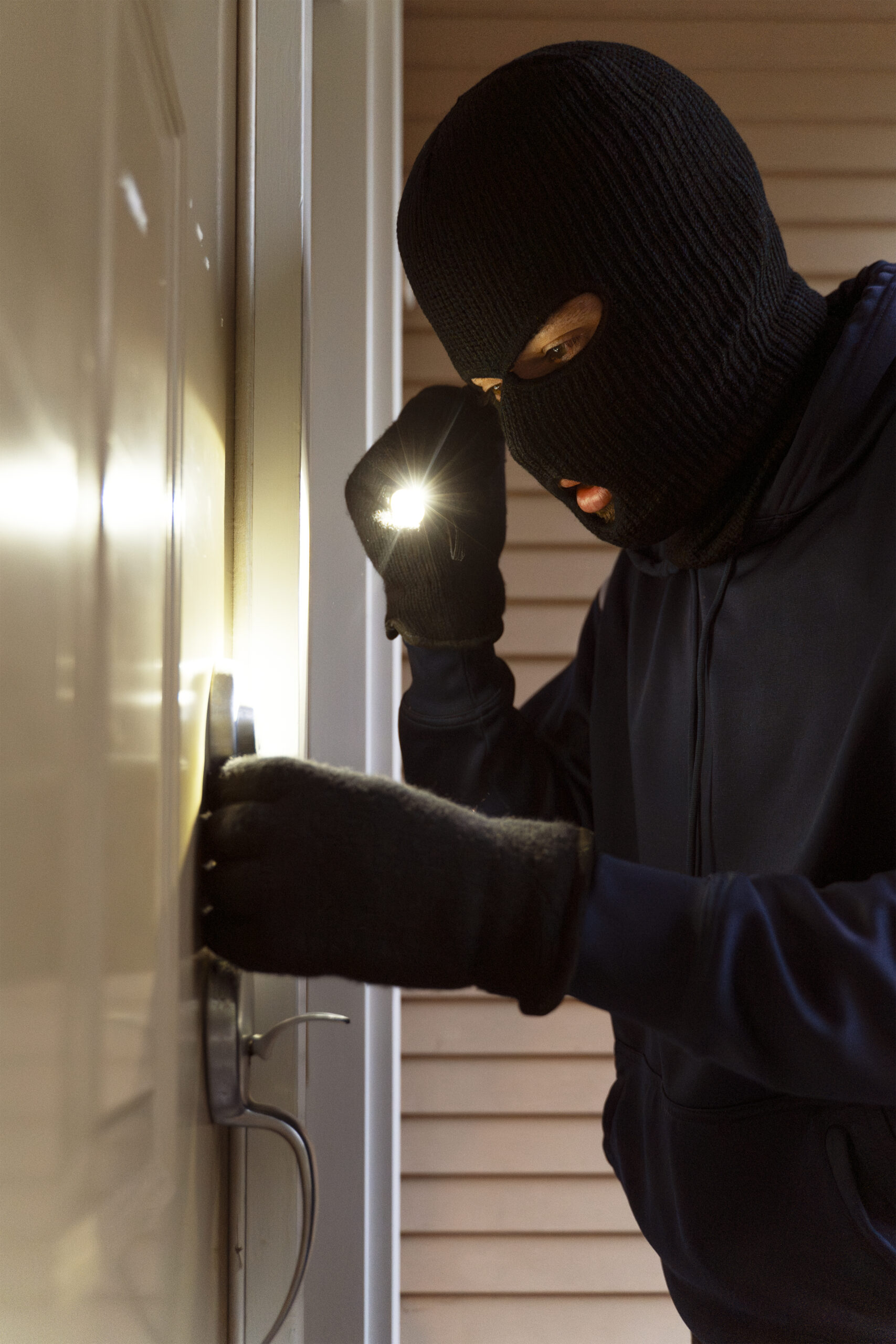 Masked burglar picking lock and entering house at night